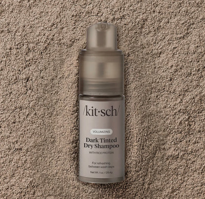 Kitsch dark tinted dry shampoo bottle on a textured beige surface